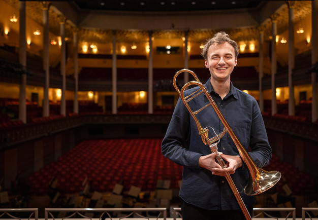 Man som håller i en trombon. Fotografi.