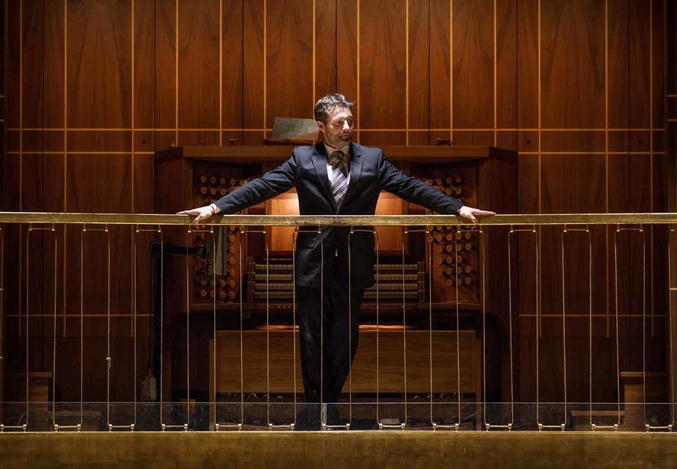 Man som står vid stor orgel. Fotgorafi.